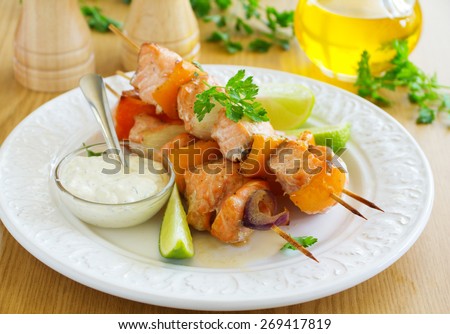 Shashlik of salmon with vegetables and white sauce.