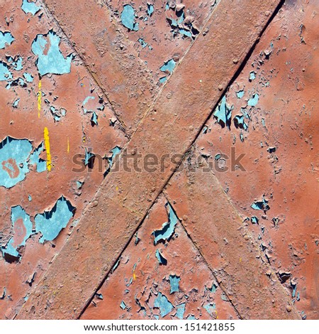 The cracked brown paint on an old metallic surface.