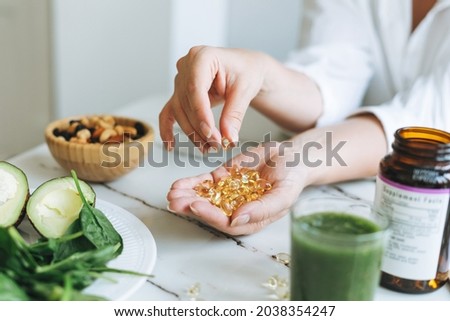 Woman doctor nutritionist hands in white shirt with omega 3, vitamin D capsules with green vegan food. The doctor prescribes a prescription for medicines and vitamins at the clinic Foto stock © 