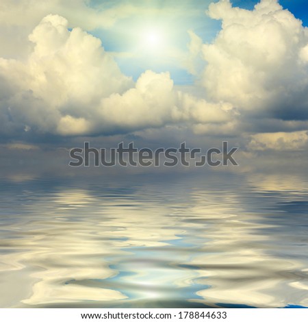 Beautiful textural clouds with shining sun, reflected in water.