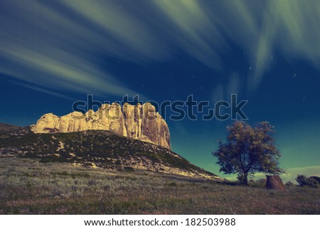Vintage picture. High cliff in a moon light with a beautiful moving clouds and lonely tree