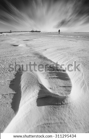 Figure of lonely man on a frozen Black sea. Winter landscape. Monochrome colors