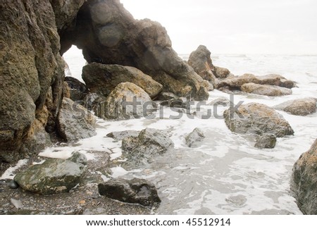 waves flowing over coastal rock formations with a natural window