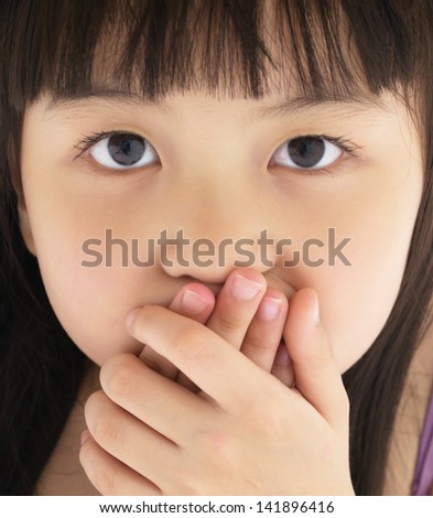 Scared little girl covering mouth with hand