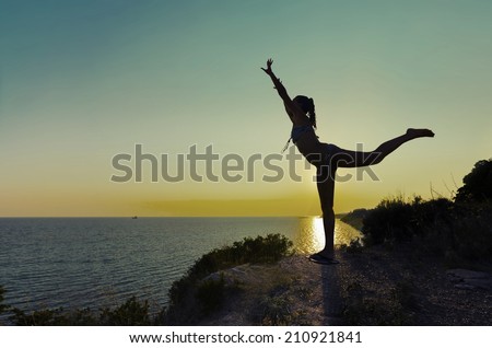 Silhouette of Joy. Silhouette of a gymnast backlit girl in balance on a beam at sunset against sea horizon, VINTAGE