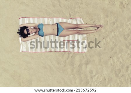 Bermuda Sunbathing, Beautiful brunette girl is sunbathing on an empty beach, aerial view from top. VINTAGE