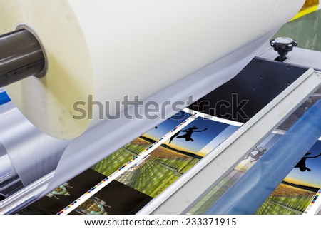 offset machine press print run at table, sheet-fed paper feeder unit. Poster laminator