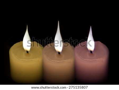 Three white candles green and purple on a black background.