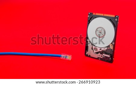 Cloud storage concept suggested by a internet network cable and a open hard disk on a red alerted background suggesting problems in accessing on line data