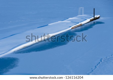 Calm and Deeply Snowed Jetty into Frozen Lake in Winter