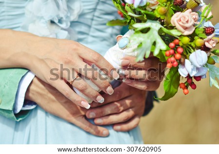 bride and groom\'s hands with beautiful wedding bouquet in warm calm colors