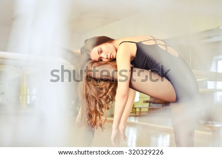 portrait of a beautiful ballerina stretching and doing exercises in ballet hall