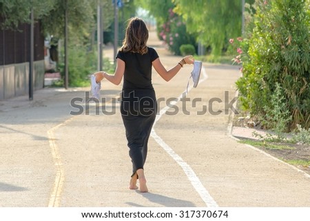 Skinny young girl on a bicycle path walks with shoes in hand