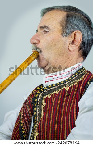 Pipe player in traditional clothing. Woodwind instrument