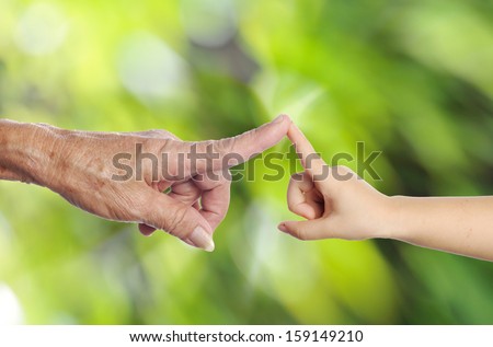 old woman hand touching a child\'s hand in green background