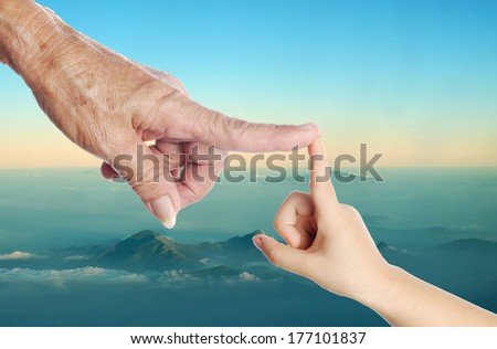 old woman hand touching a child\'s hand on blue sky and  Landscape background