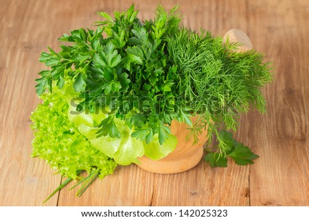 Green herbs in a pounder isolated on wooden table