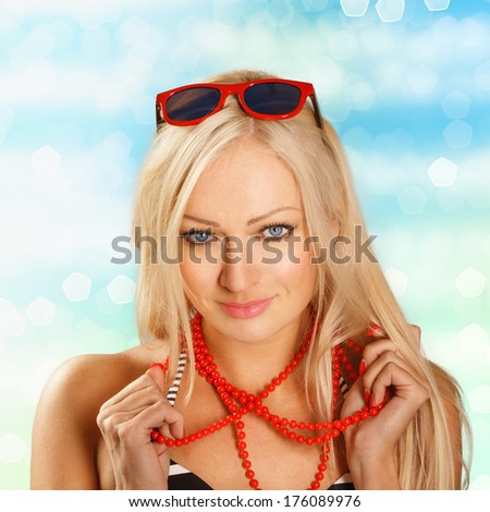 Sexy bikini woman on the seaside holding her red beads. Shining water background.