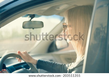 blonde woman with a sunglasses on driving a car. sunset light, toning