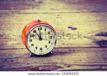 Beautiful old orange alarm clock on the wooden floor