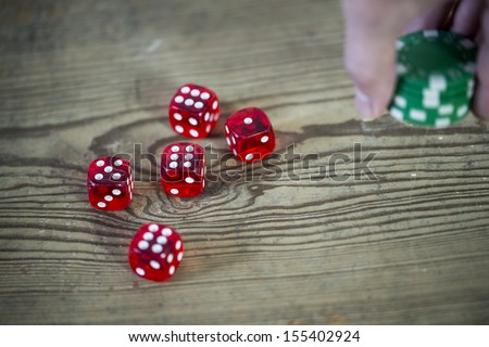 dice, chips in the hand and wooden table