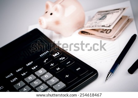Business Charts with calculator, dollars money, piggy box  money box and pen on white background