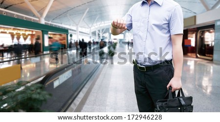 Young Businessman is waiting in the airport waiting hal and he checks the time on his watch.