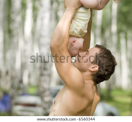 Father play with baby outdoors, he hold him in hands head first, nose to nose