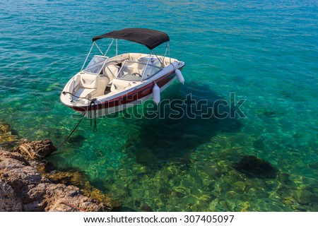 Small white boat floating in clean water near shore on a sunny day