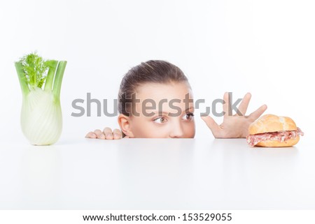 Hesitating woman making decision between healthy salad and fast food, over white background