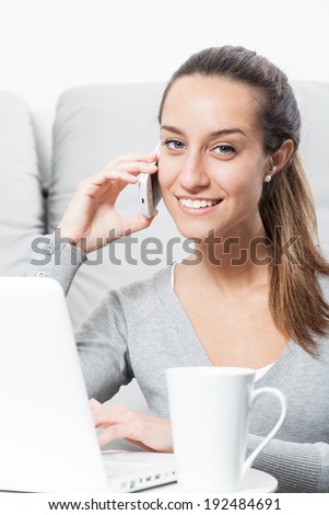 Beautiful woman talking on the telephone and working at home