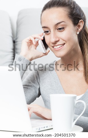 Beautiful woman talking on the telephone and working at home