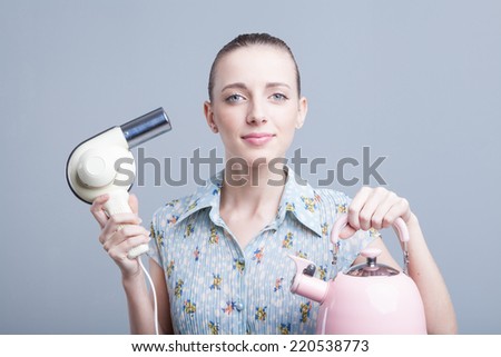 Funny girl in curlers with hairdryer styling hair