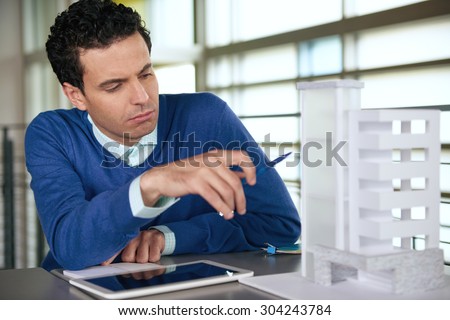 middle eastern descent businessman looking at an architecture model