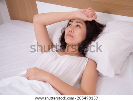 female on bed with stress, insomnia, hangover in bedroom
