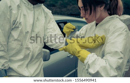 Woman taping bacteriological protective gloves to a man