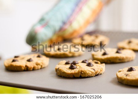 Closeup of woman with colorful kitchen gloves holding a homemade baked cookies tray