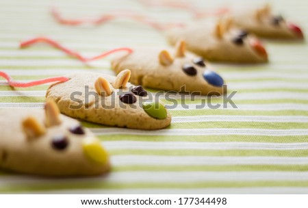 Cookies with mouse shaped and red licorice tail over green striped tablecloth