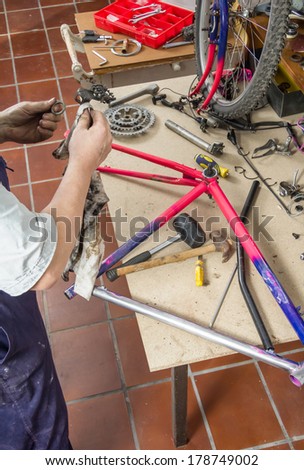 Real bicycle mechanic cleaning bike parts over workshop table in the repair process