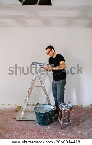 Mason working picking plaster with spatula