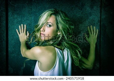 Closeup of young beautiful woman scared with her hands over a metallic dark door