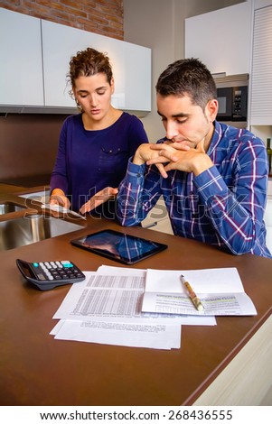 Unemployed young couple with many debts reviewing their bills. Financial family problems concept.
