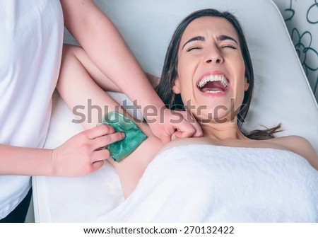 Portrait of young beautiful woman shouting by depilation armpit pain in a beauty salon