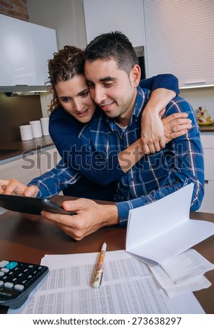 Cheerful young couple using digital tablet at kitchen home after the work. Family leisure home concept.