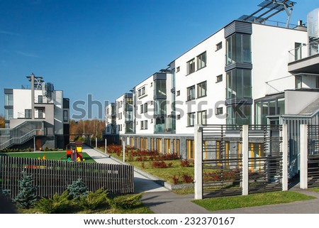 New built block of residential buildings with common space at yard under clear blue sky