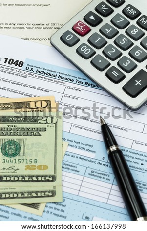 Tax form with pen, calculator, and dollar banknote taxation concept