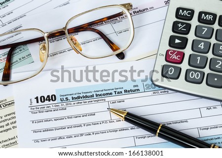 Tax form with pen, calculator, and glasses taxation concept