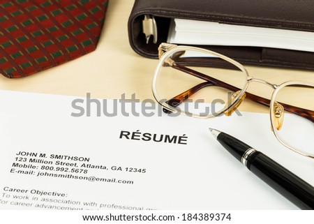 Resume, pen, neck tie, glasses, and notebook