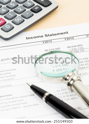 Income statement financial report with magnifier, pen, and calculator; document is mock-up