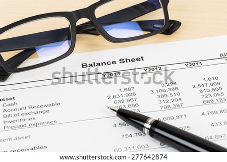Balance sheet financial report with pen, and glasses; document is mock-up